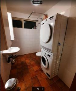 a bathroom with a toilet and a washing machine at Thorshamar - Car Included in Reykjavík