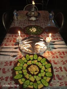 een tafel met borden eten erop met kaarsen bij oasis panorama in Mandīshah