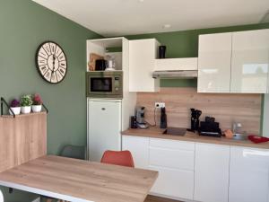 een keuken met witte kasten en een klok aan de muur bij Les Gîtes de Bellevue in Nueil-sous-les-Aubiers