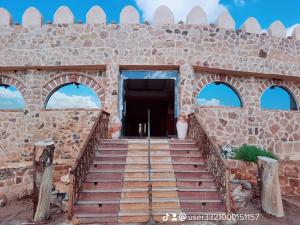 un edificio de piedra con escaleras que conducen a una puerta en oasis panorama en Mandīshah