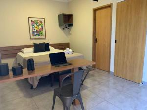 een slaapkamer met een bed en een laptop op een bureau bij Studio Standard l AO LADO SHOPPING in Três Lagoas