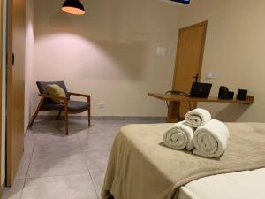 a bedroom with a bed and a chair and a table at Studio Standard l AO LADO SHOPPING in Três Lagoas
