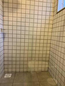 a bathroom with white tiled walls and a window at Studio Standard l AO LADO SHOPPING in Três Lagoas