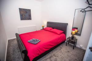 a bedroom with a red bed with a red blanket at Libra House retreat, Caswell Bay in Swansea