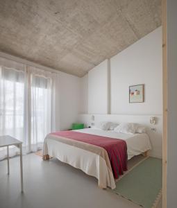 Ses Sucreres Small & Slow Hotel في فيريريس: غرفة نوم بيضاء مع سرير كبير مع بطانية حمراء