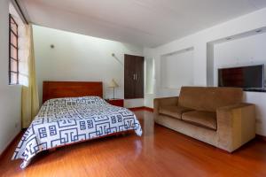 een slaapkamer met een bed en een bank bij Apartaestudios La Candelaria in Bogota