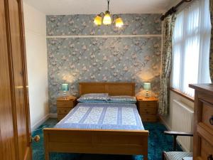 a bedroom with a bed and a wall with flowers at Quirky Cottage with Private Garden Nr New Quay Cardigan Bay in Llandysul