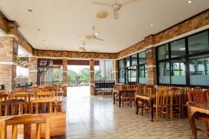 Buengngarm Resort : مطعم فيه كراسي وطاولات خشبية ونوافذ