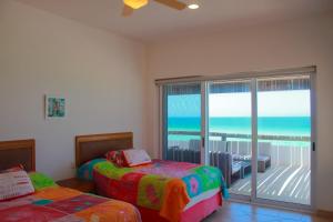 Nisiros Spacious Beachfront home في تشيكشولوب: غرفة نوم بسريرين وشرفة مطلة على المحيط