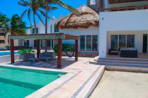 Villa con piscina y sombrilla de paja en Nisiros Spacious Beachfront home, en Chicxulub