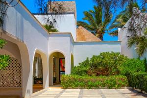 Nisiros Spacious Beachfront home في تشيكشولوب: بيت ابيض فيه ساحة و نخيل