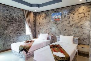 2 camas en una habitación con una pared de piedra en Buengngarm Resort 