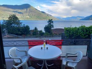 a table and chairs on a balcony with a view of a lake at House1919 Via Valmara 14 in Brissago