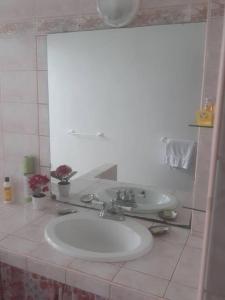 a white bathroom with a sink and a mirror at F3 Papeete centre-ville in Papeete