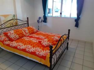 a bed with an orange and white comforter and a window at F3 Papeete centre-ville in Papeete