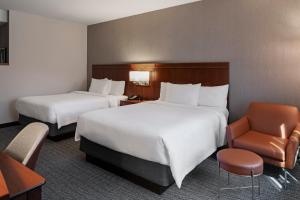 um quarto de hotel com duas camas e uma cadeira em Courtyard Long Beach Airport em Long Beach