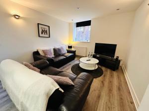 a living room with a leather couch and a tv at West Street Mews - Serviced Accommodation in Exeter