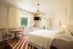 a bedroom with a bed and a table and a kitchen at Secreto Boutique Hotel in Campos do Jordão