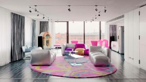 a living room with pink chairs and a rug at nhow Berlin in Berlin