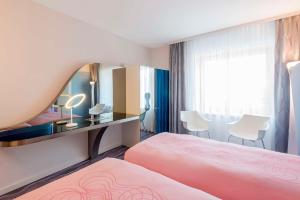 Habitación de hotel con cama rosa y espejo en nhow Berlin en Berlín