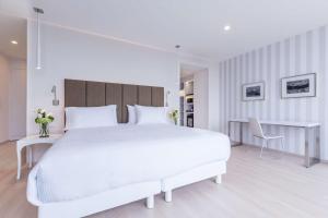 Un dormitorio blanco con una gran cama blanca y escritorios en NH Puebla FINSA, en Puebla