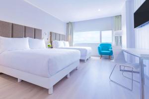 普埃布拉的住宿－NH Puebla FINSA，白色卧室配有两张床和蓝色椅子
