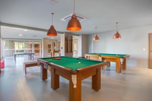 due tavoli da biliardo in una stanza con palline da ping pong di Laghetto Golden a Gramado