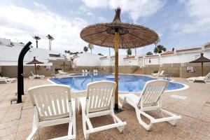 a pair of chairs and an umbrella next to a swimming pool at Child-friendly, 3-bedroom apartment with garden near the Aqualand in Adeje
