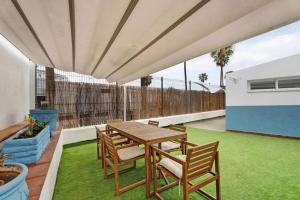 an outdoor patio with a wooden table and chairs at Child-friendly, 3-bedroom apartment with garden near the Aqualand in Adeje