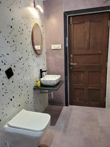 ein Bad mit einem WC, einem Waschbecken und einer Tür in der Unterkunft Forest County Resort in Mahabaleshwar
