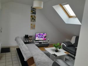 een woonkamer met een bank en een tv bij Appartement meublé à 30 minutes de Paris in Mantes-la-Jolie