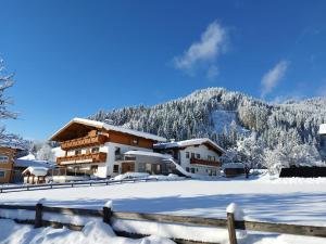 un edificio cubierto de nieve frente a una montaña en Landhaus Maurer, en Wagrain