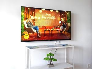 una televisione su un muro con una persona seduta su una sedia di Tivat Center SeaView Apartment a Tivat