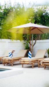 two lounge chairs and an umbrella next to a pool at The White Bay Lombok in Kuta Lombok
