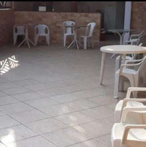 un patio con mesas y sillas blancas y mesas y sillas en Pousada Canto Feliz, en Peruíbe