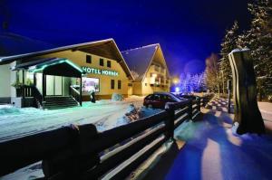 a building with a fence in the snow at night at Hotel Horník in Vlachovice