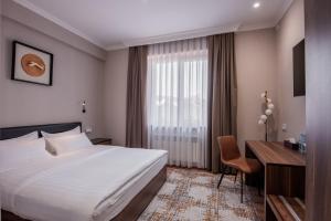 Pokój hotelowy z łóżkiem i biurkiem w obiekcie Silk Road Tashkent w Taszkiencie
