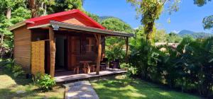 a small wooden cabin with a red roof at Bungalow le Balisier in Pointe-Noire