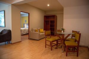 1 dormitorio y sala de estar con mesa y sillas. en HOTEL SUDAMERICANA INN en Tacna