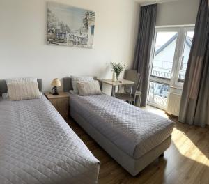 a bedroom with two beds and a table and a window at Barka Pokoje i Apartamenty in Karwia