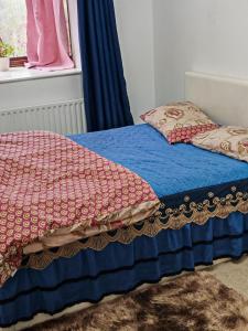 a bed with a blue blanket and pillows on it at Spacious flat with free parking in Croydon in Croydon