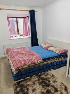 a bed in a room with a window and a bedspread at Spacious flat with free parking in Croydon in Croydon