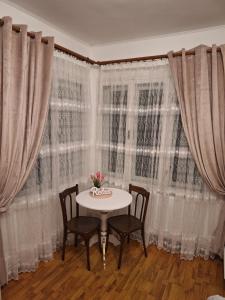 un tavolo e sedie di fronte a una finestra con tende di Parc Apart Vatra Dornei a Vatra Dornei