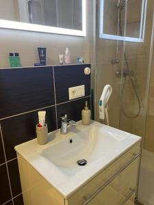 La salle de bains est pourvue d'un lavabo blanc et d'une douche. dans l'établissement Apartmán s manželskou posteľou, à Bratislava