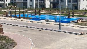 a swimming pool with blue water in a city at Duplex with Garden in Amwaj Sidi Abdel-Rahman-Beach & Pool Passes Included! in El Alamein