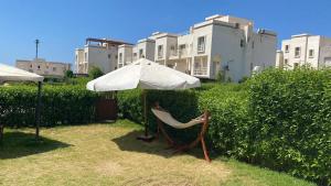 a chair under an umbrella at Duplex with Garden in Amwaj Sidi Abdel-Rahman-Beach & Pool Passes Included! in El Alamein