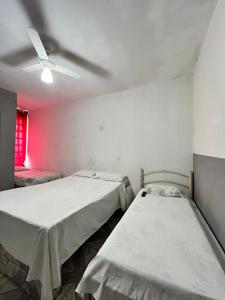 two beds in a room with a ceiling fan at Pousada Sol in Goiânia