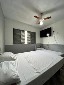 1 dormitorio con 1 cama blanca y ventilador de techo en Pousada Sol, en Goiânia