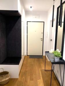 a hallway with a white door and a table with a plant at Apartaments Airport Komputerowa Premium in Warsaw