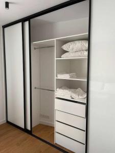 a mirror reflection of a closet with white shelves at Apartaments Airport Komputerowa Premium in Warsaw